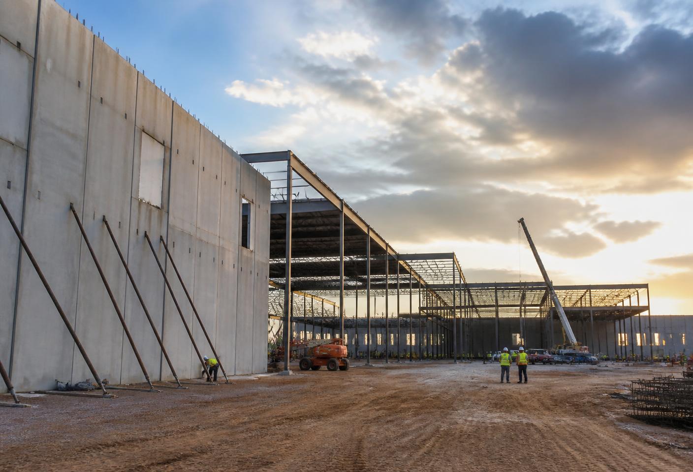 Commercial construction site with tilt-up concrete panels and steel framing in warm Arizona light